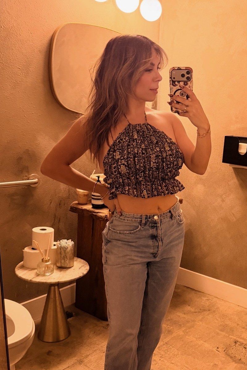After photo of @_tamaracorona, a mirror selfie in a printed halter top and light jeans.
